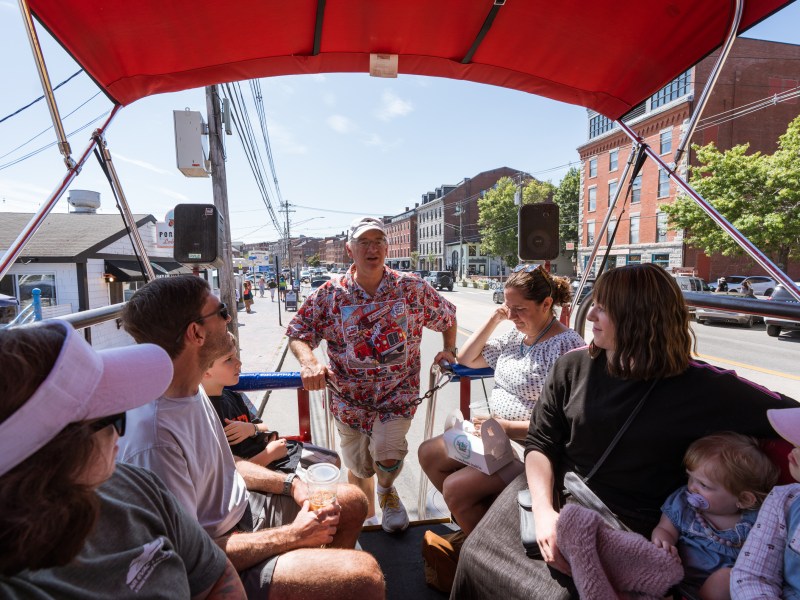 Group of people sitting on a trolley with guide on a sunny day.
