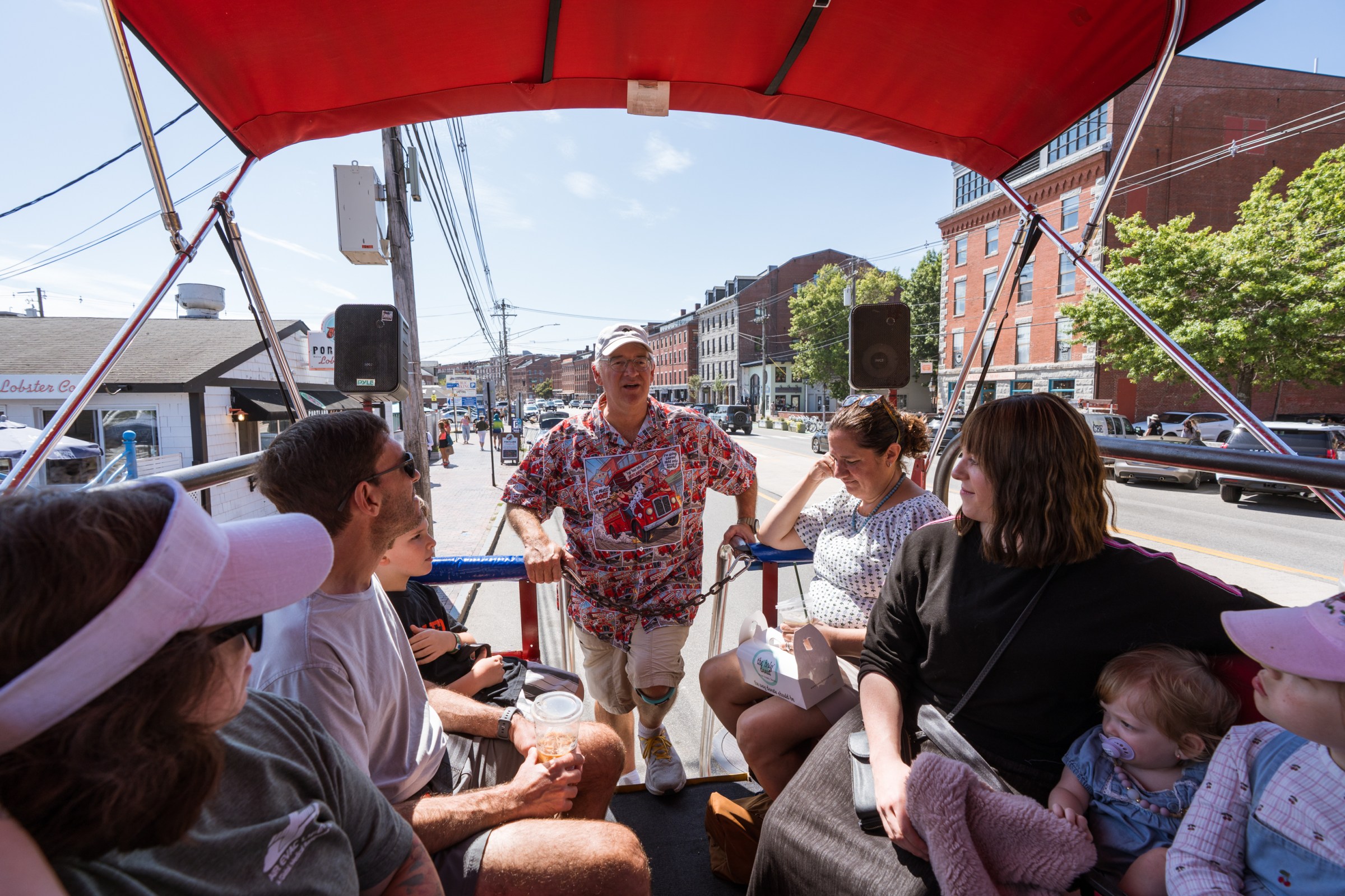 Group of people sitting on a trolley with guide on a sunny day.