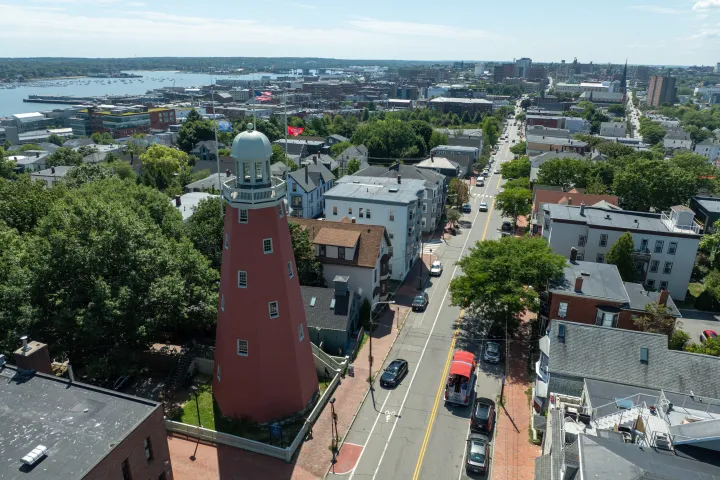 Aerial view of a cityscape with a tall, red, octagonal tower and surrounding buildings.