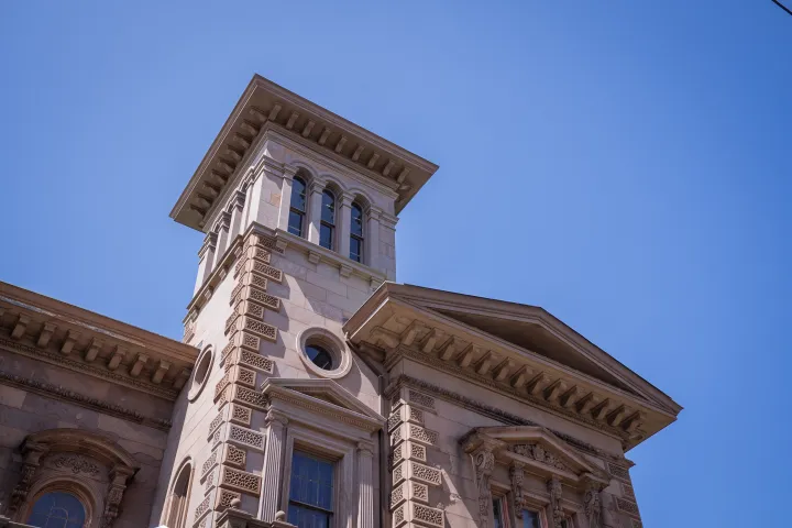 Historic stone building with a tower and blue sky backdrop.
